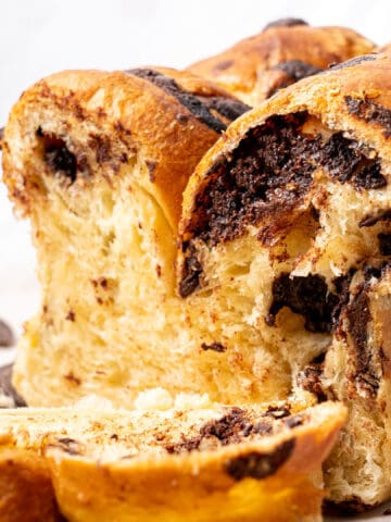 Chocolate chip brioche cut half on a baking sheet.