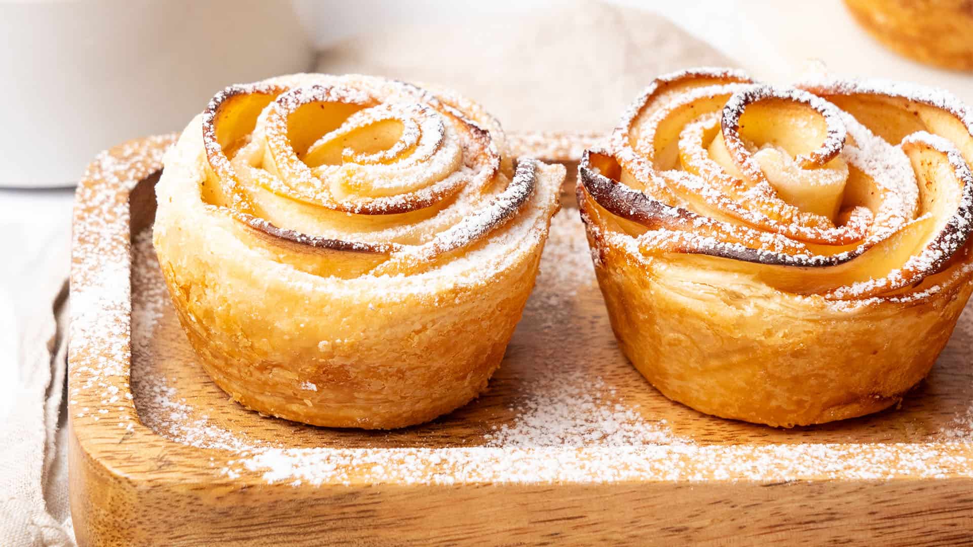 apple roses with puff pastry on a wooden tray.