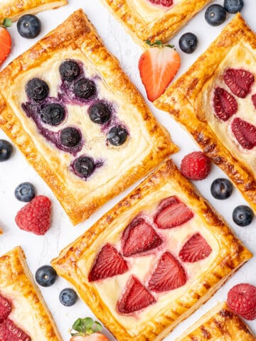 Cream Cheese Puff Pastry Danish with berries on a cutting board.