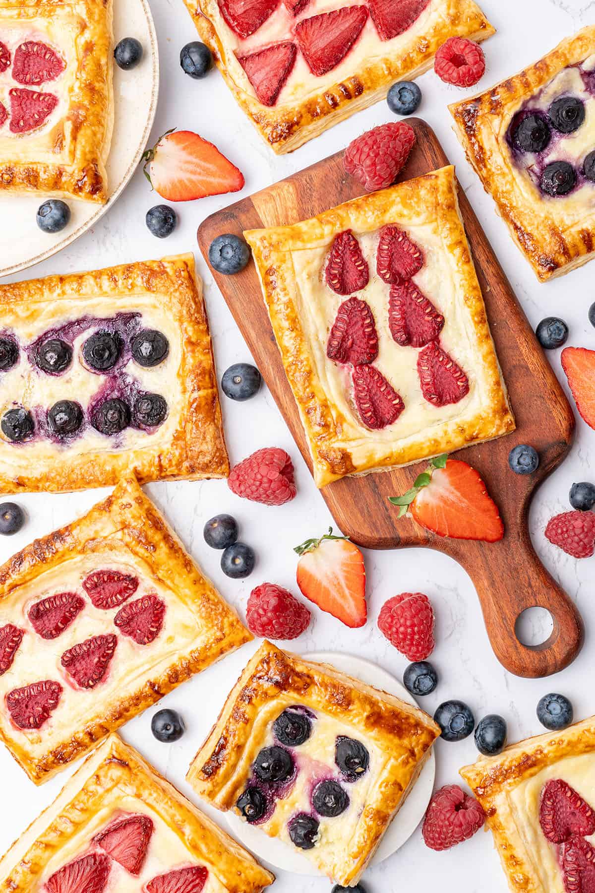 Cream Cheese Puff Pastry Danish with berries on a cutting board.