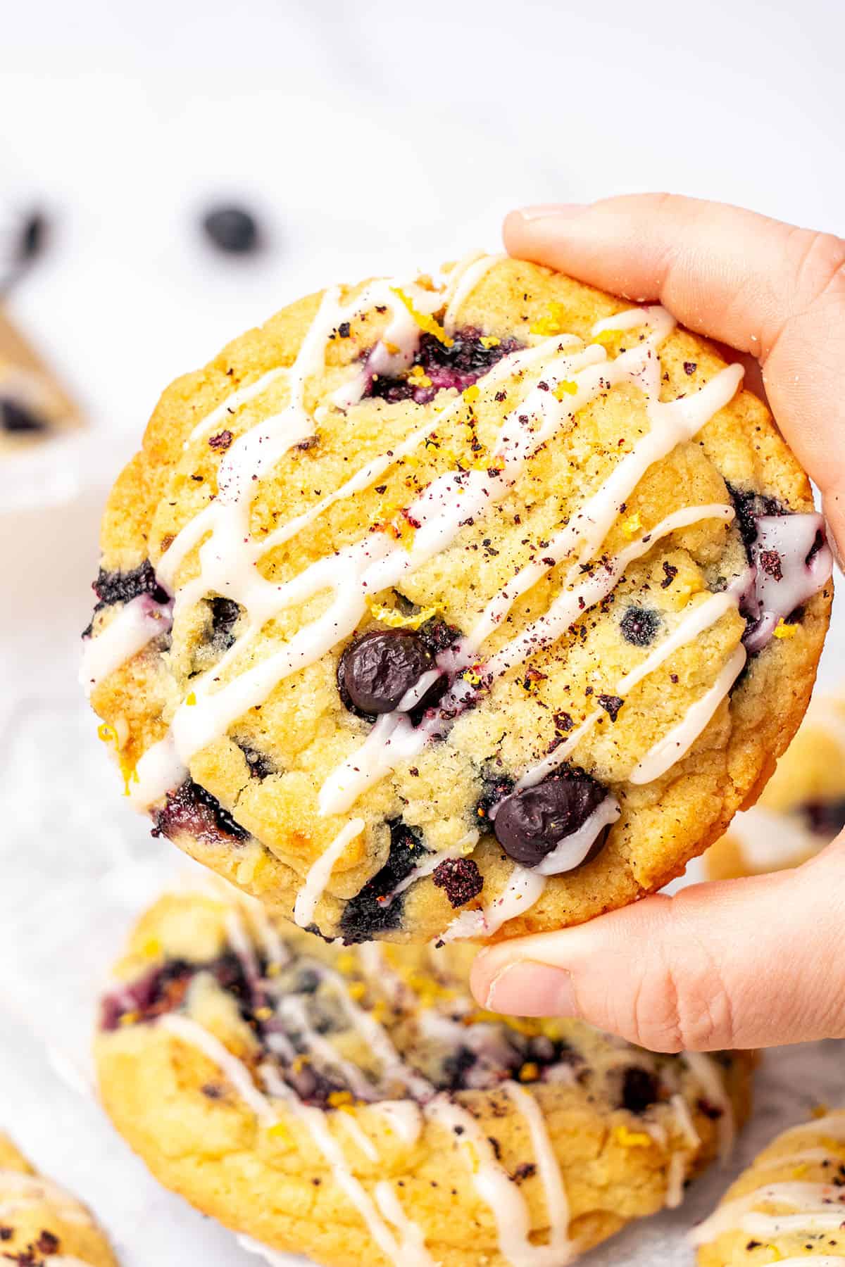 a hand is holding a lemon blueberry cookie.