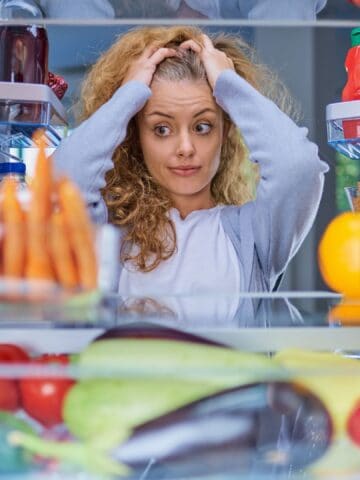 Worried woman in front of the fridge.