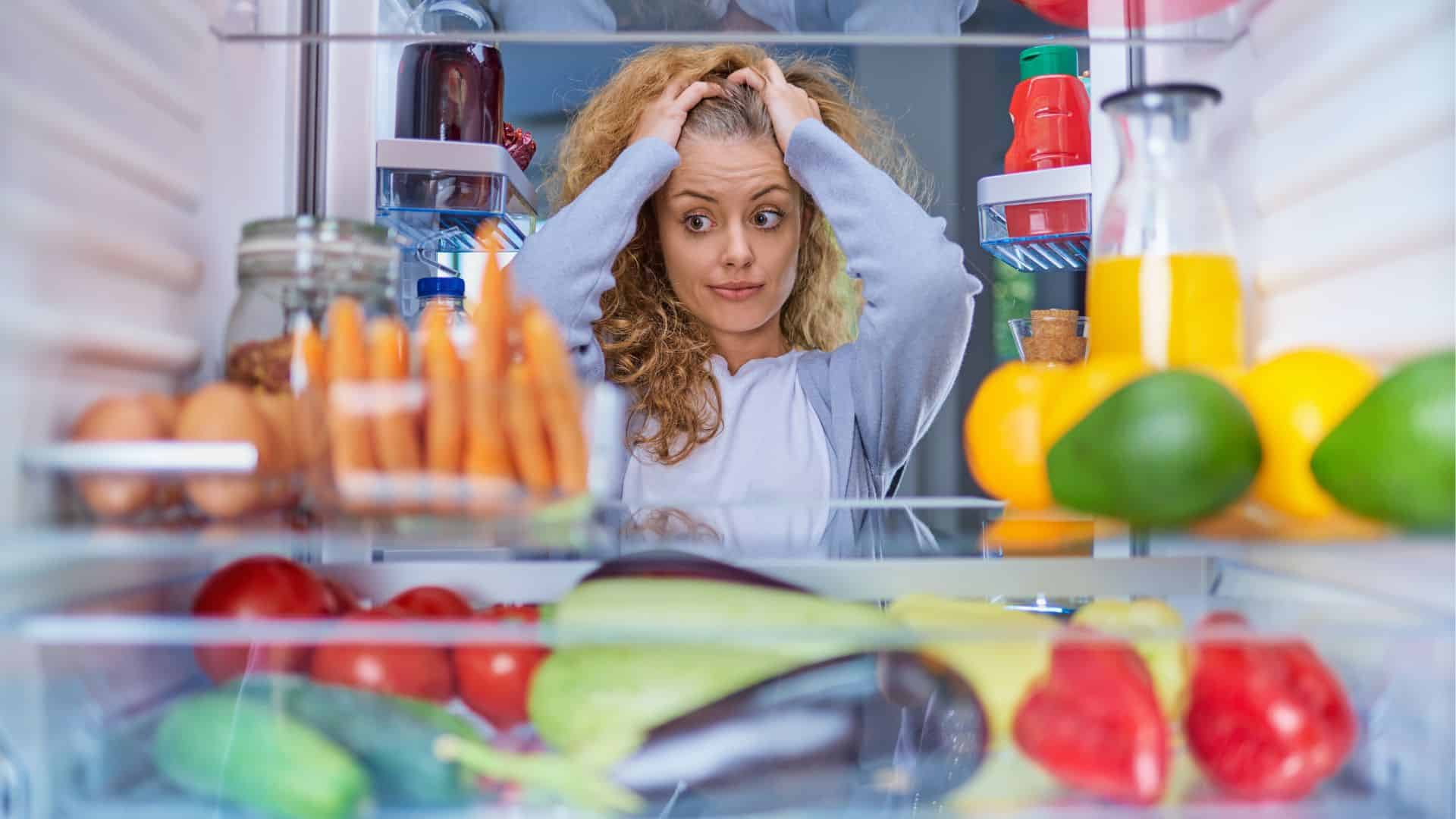 Worried woman in front of the fridge.