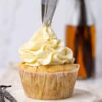 Piping American butter cream frosting on a cupcake.