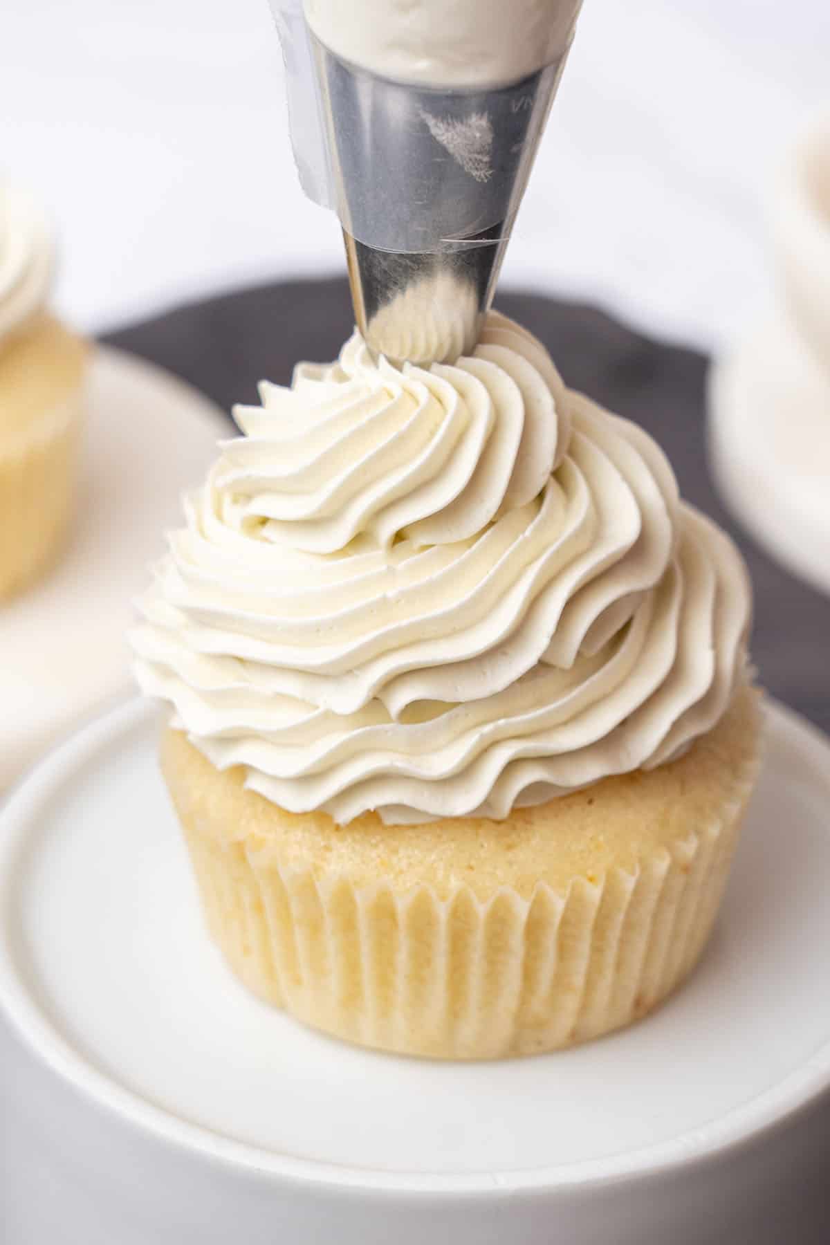 Piping Swiss meringue buttercream on a cupcake.