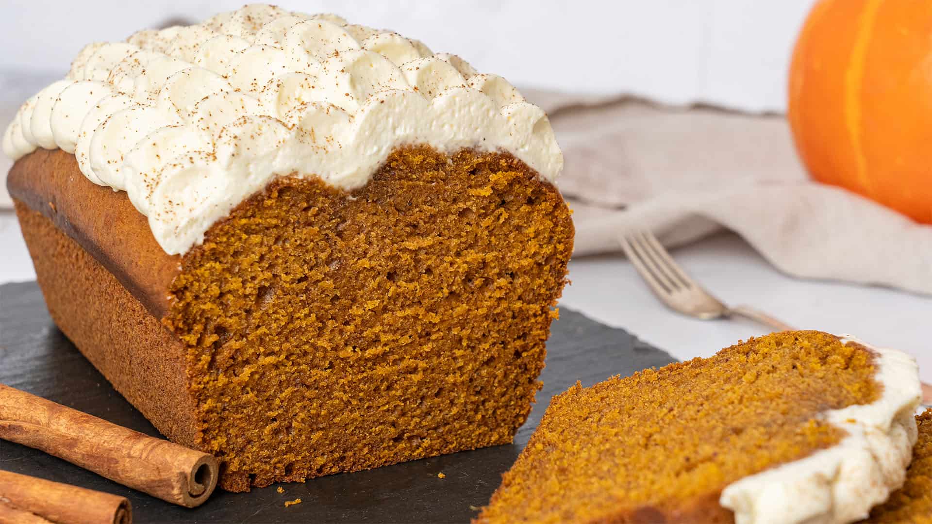 pumpkin bread with cream cheese frosting on a baking paper.