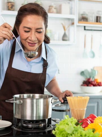old woman tasting a food in kitchen.