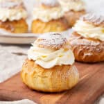 A few cream puffs on a a cutting board.