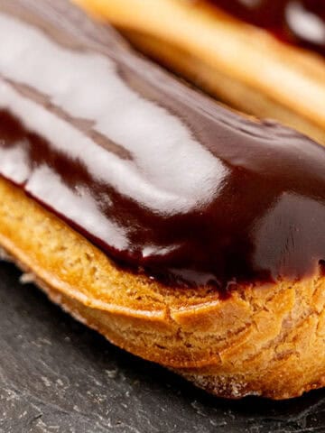 Eclairs covered with chocolate glaze and filled with pastry cream.