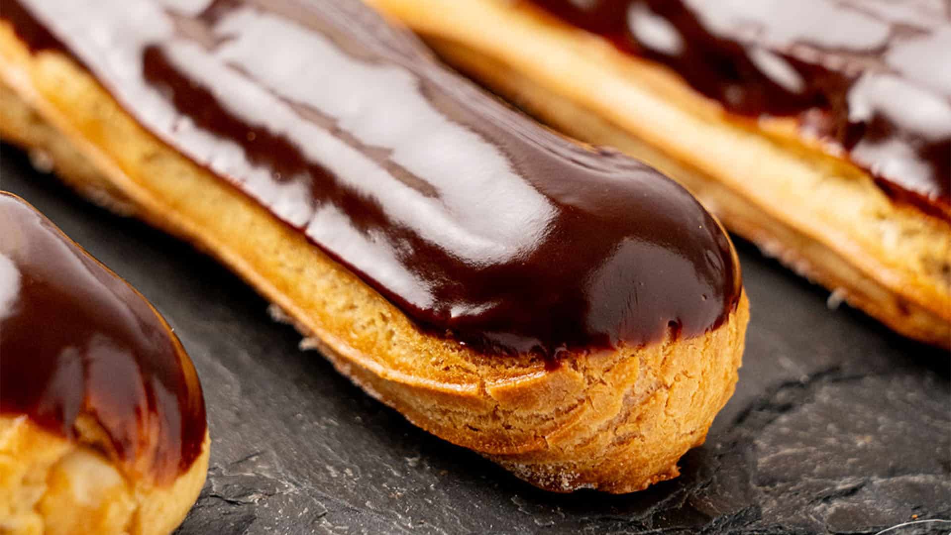 Eclairs covered with chocolate glaze and filled with pastry cream.