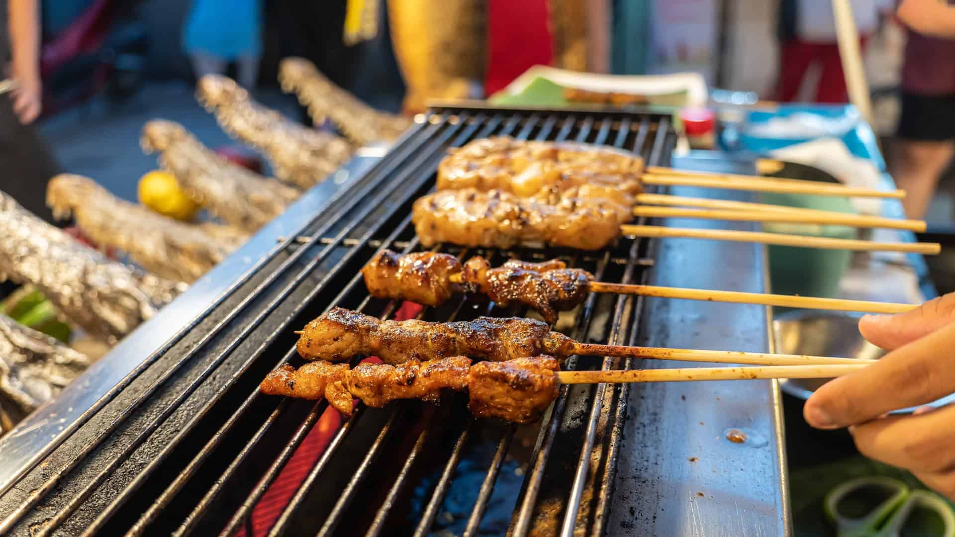 crocodile skewers being cooked on a grill