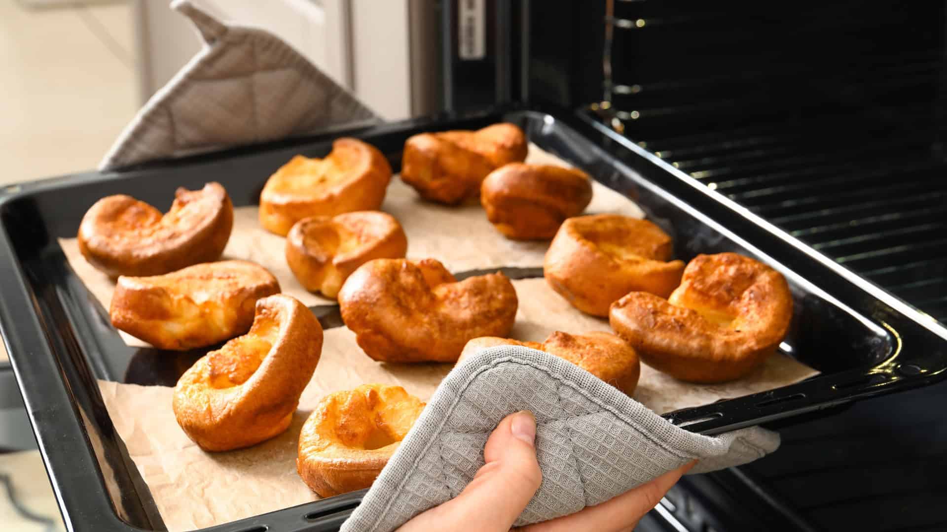 woman pulling a tray of yorkshire pudding out of the oven