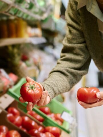 woman selecting ripe tomatoes at the grocery store