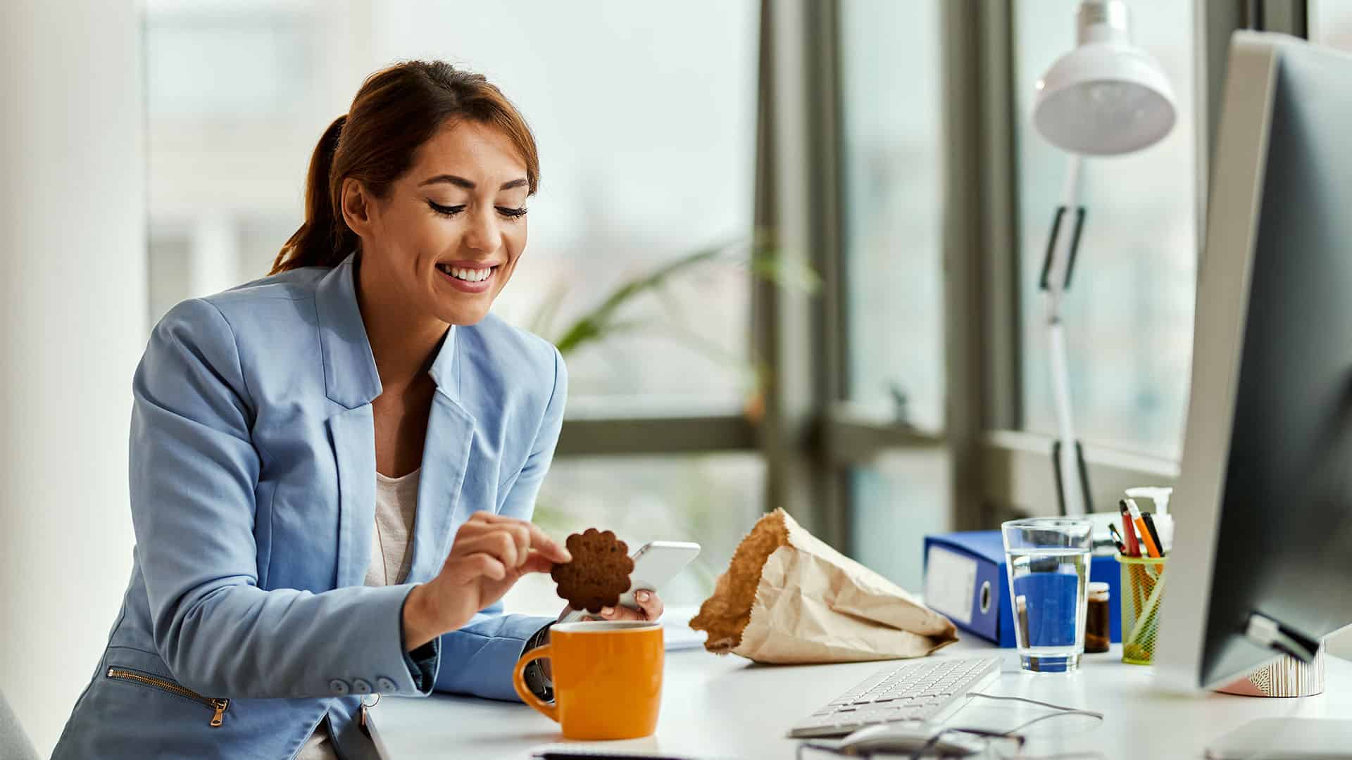 woman eating cookie in office.