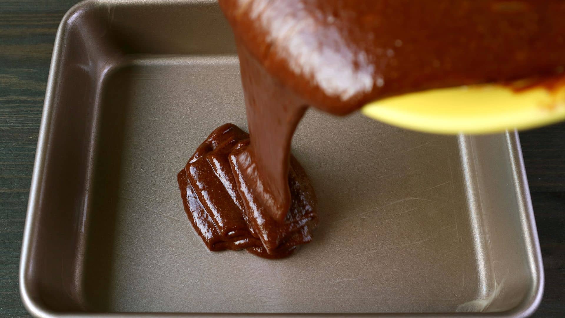Velvety caramel sauce being poured into a baking pan for dessert preparation.