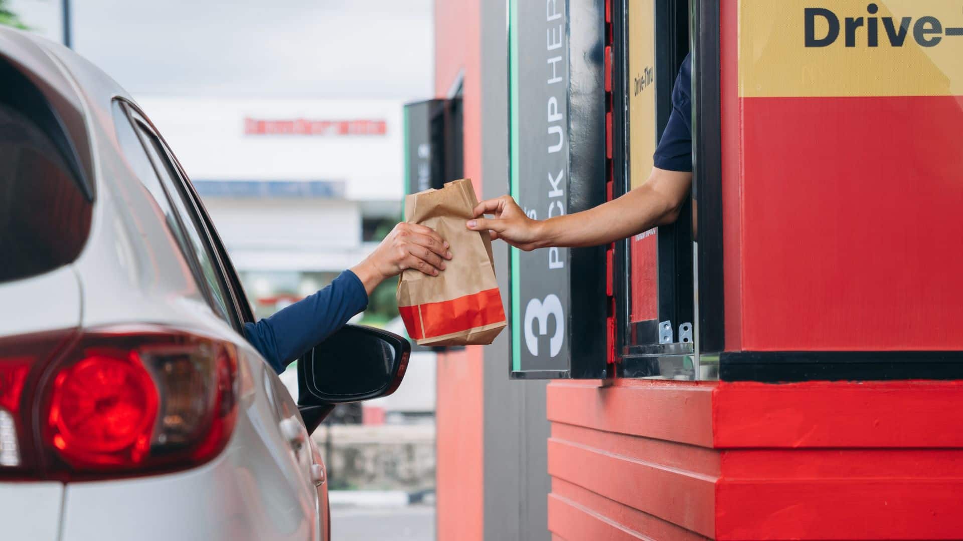 Man receiving food at drive thru counter
