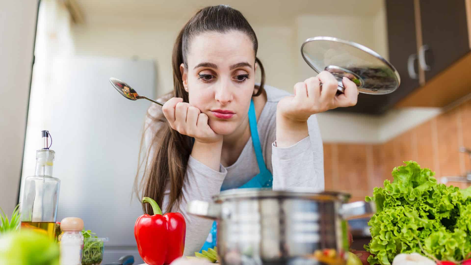 Unhappy woman looking at pot in kitchen