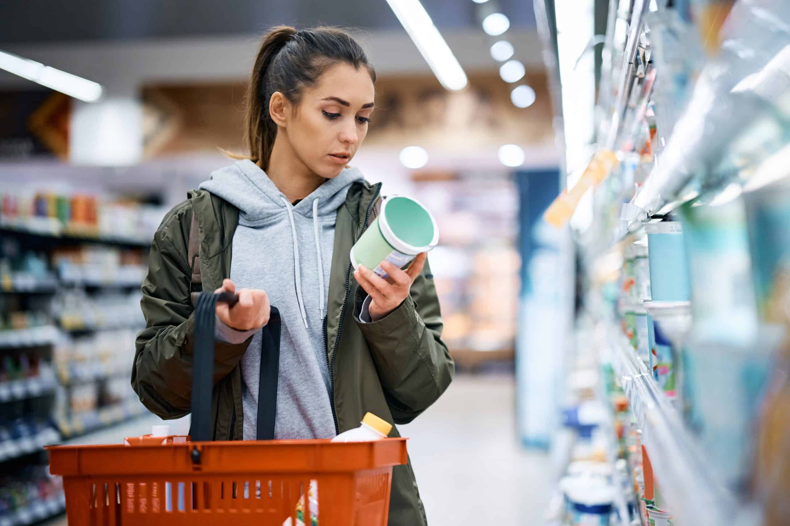 young woman buying dairy, reading label