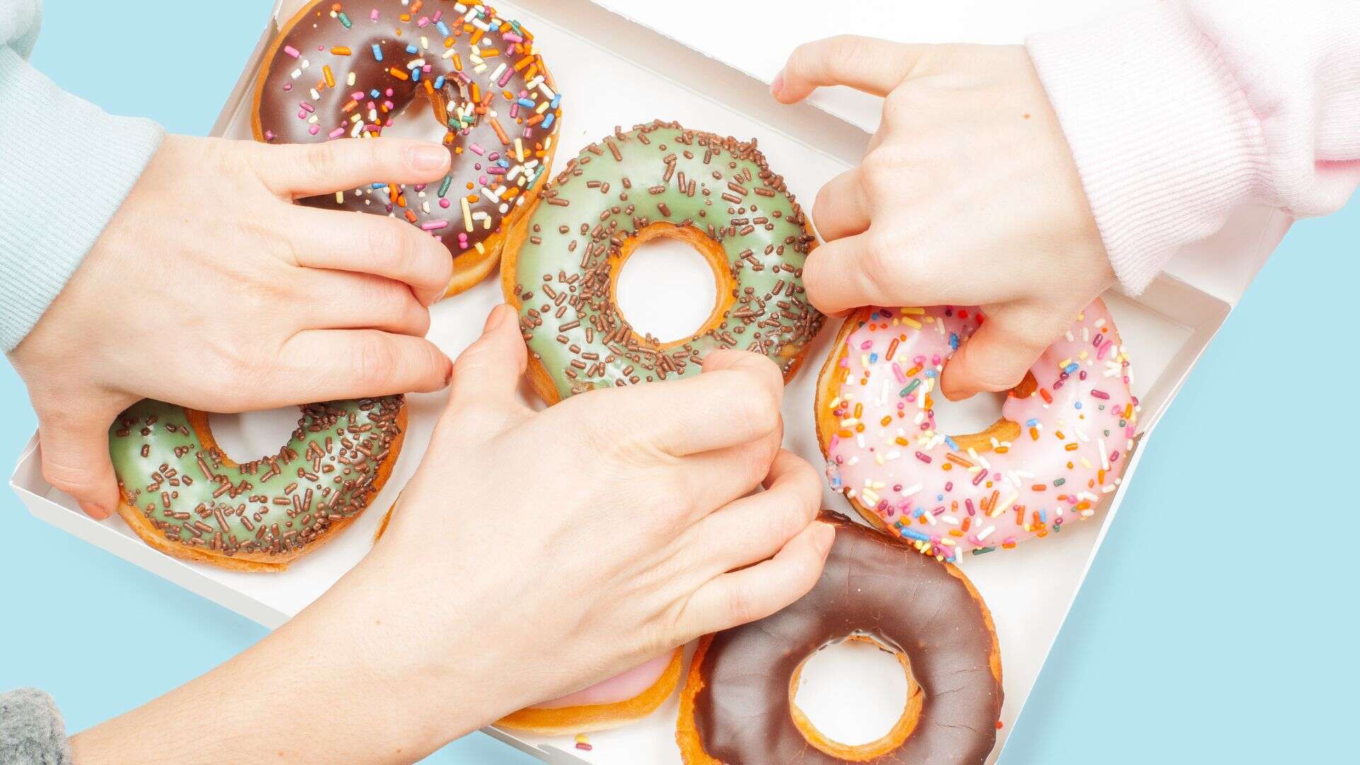 many hands grabbing donuts