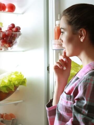 woman opening the fridge and thinking