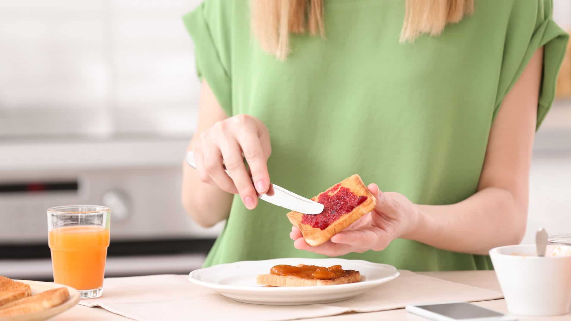 woman putting jam on toast