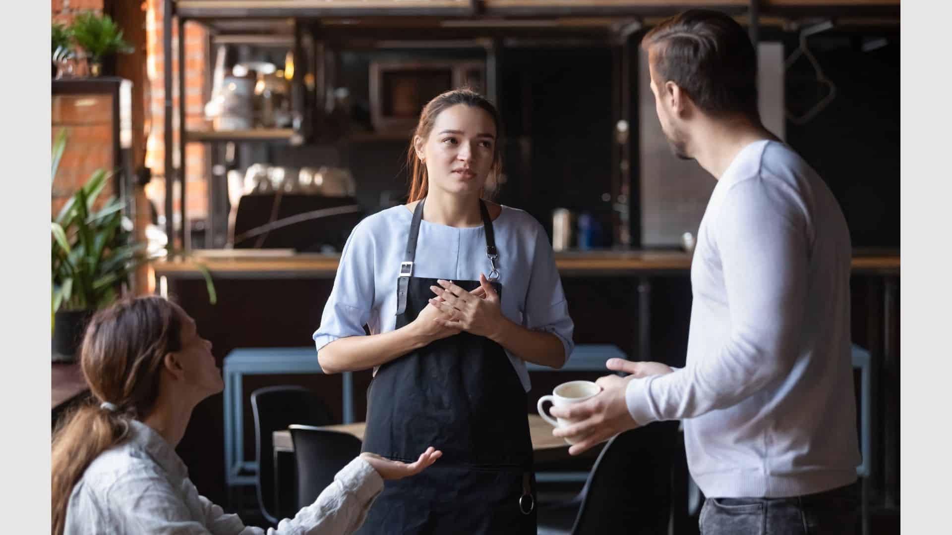 Angry restaurant couple talking with waiting staff
