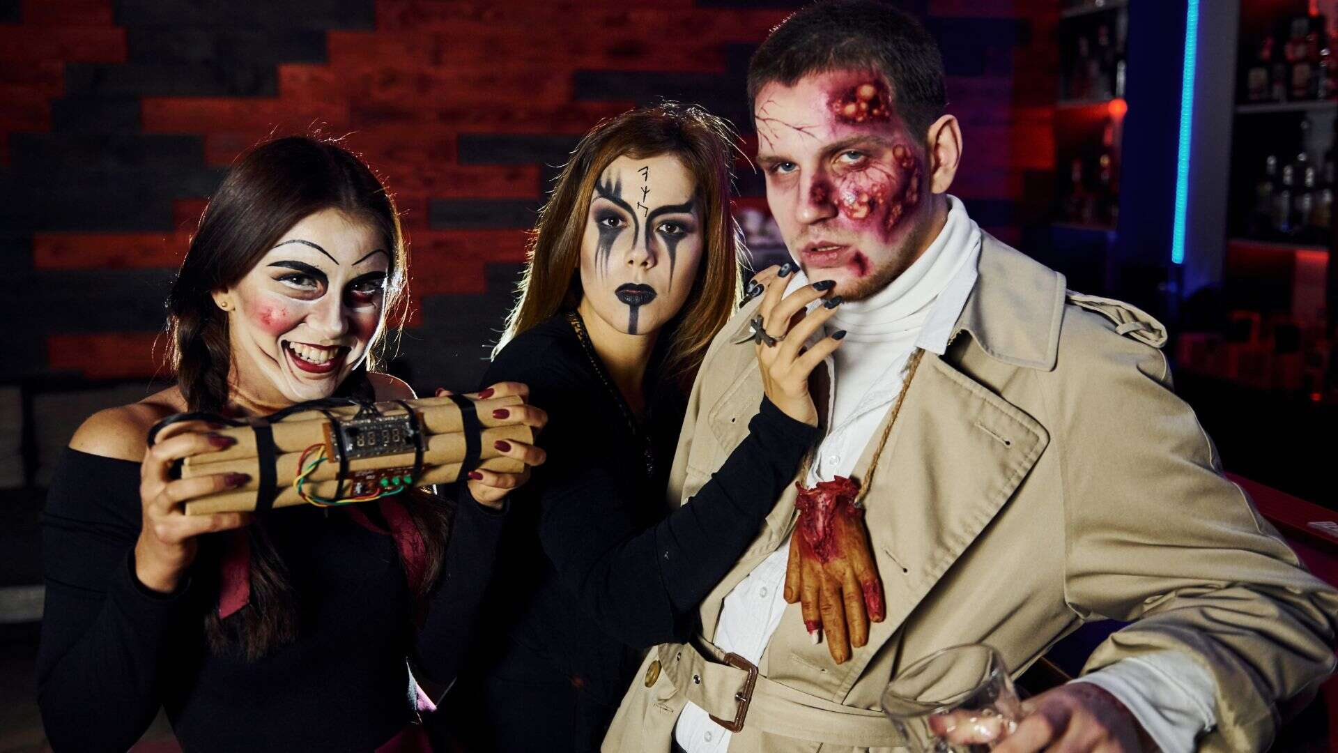 Friends with bomb in hands is on the thematic halloween party in scary makeup and costumes.