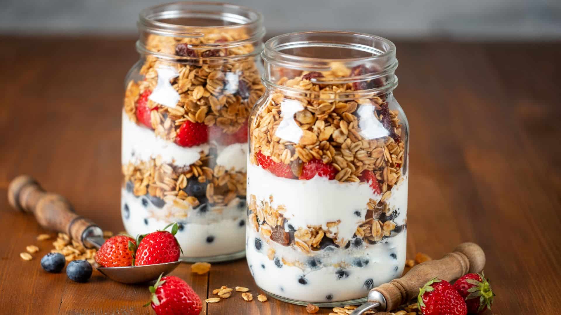 Granola Parfait with Yogurt, oat granola, fresh berries and honey in tall glass jar