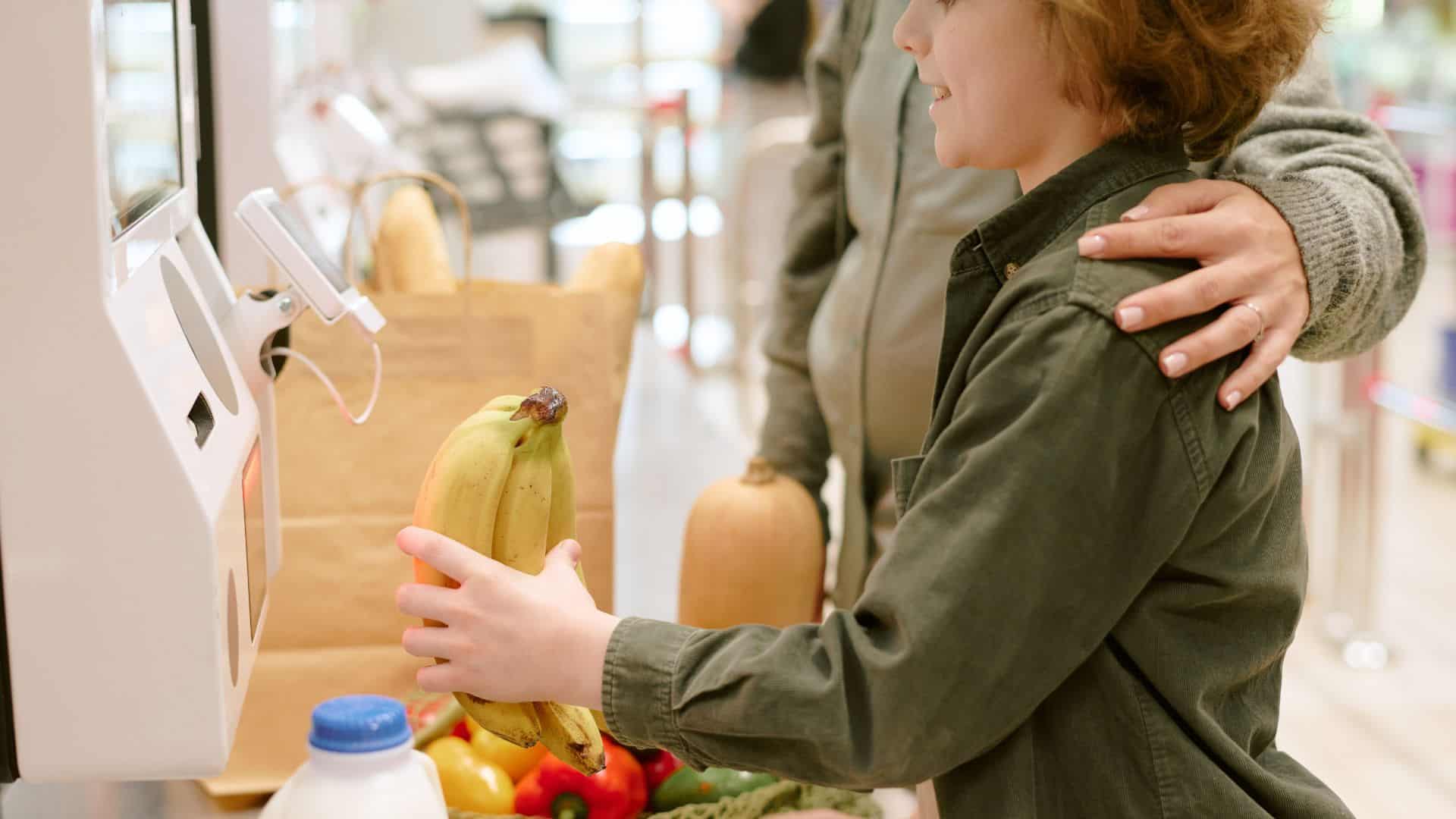 Young boy picking out groceries at self-checkout machine