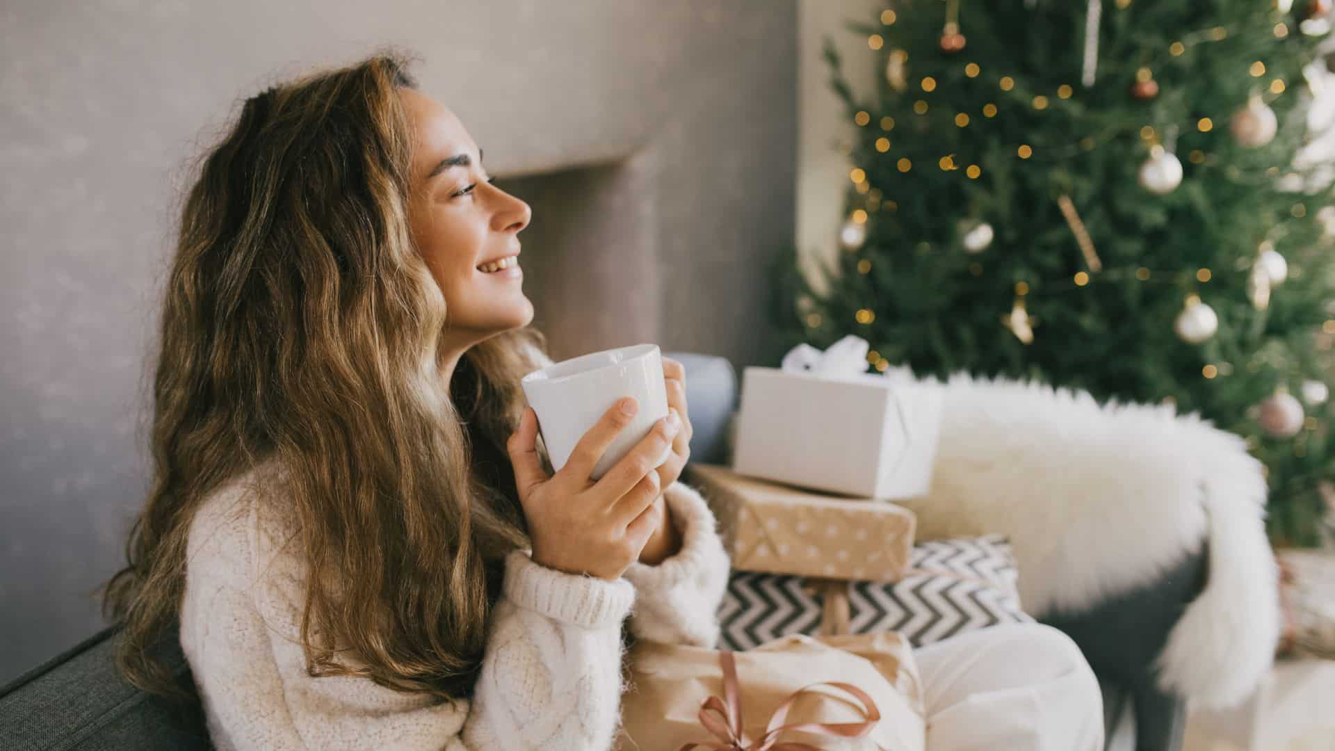 Young woman drinking hot coffee sitting on couch