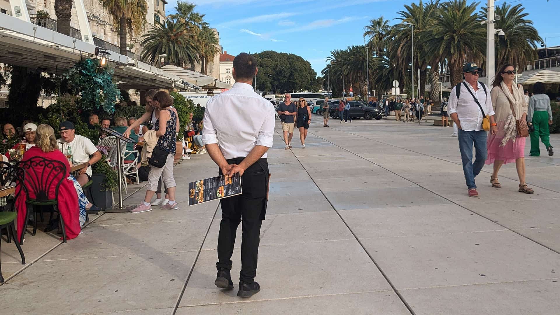 waiter waiting for tourist in front of a restaurant.