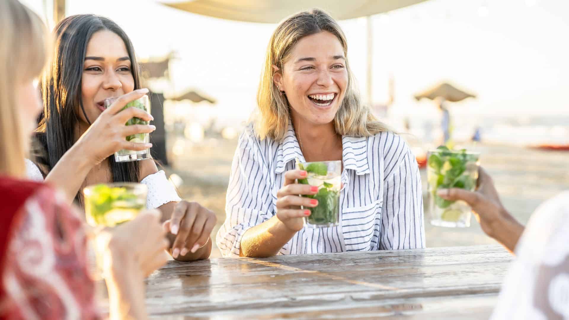 woman drinking mojito at beach with friends