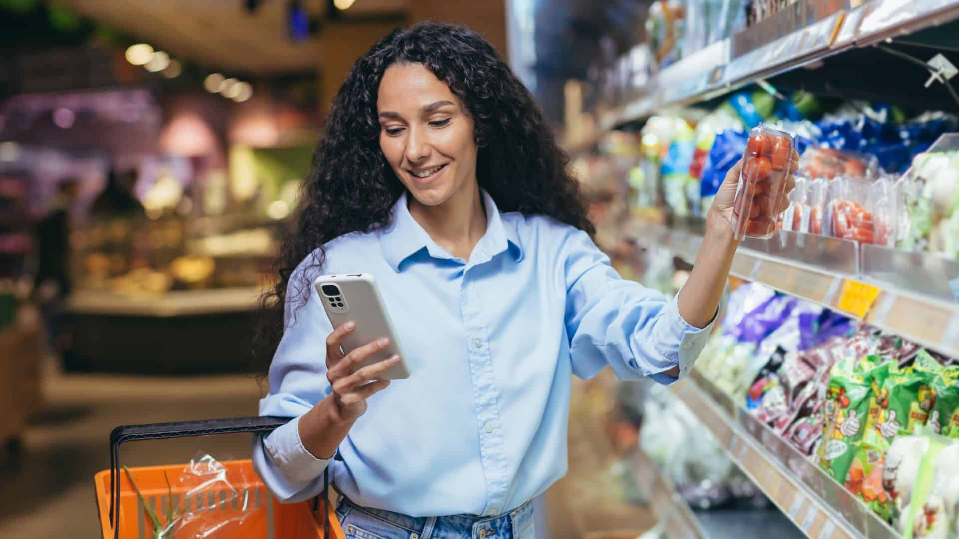 woman is standing in a supermarket with a basket near the refrigerator with vegetables