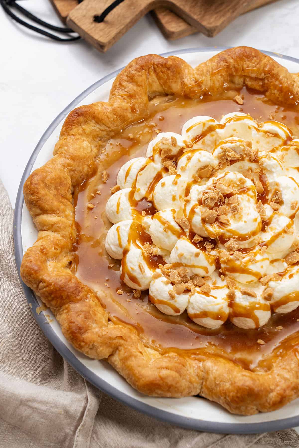 Creamy caramel apple pie with whipped cream and toasted nuts, packed with flavors and textures.