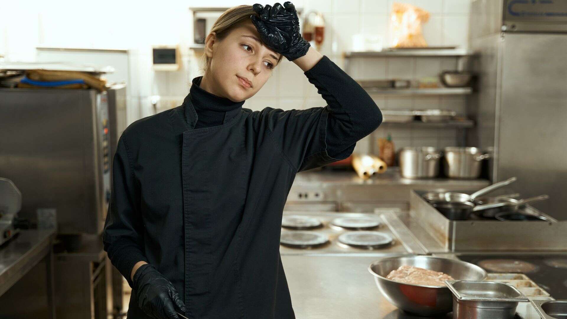 Tired chef stands at the cutting table with a knife
