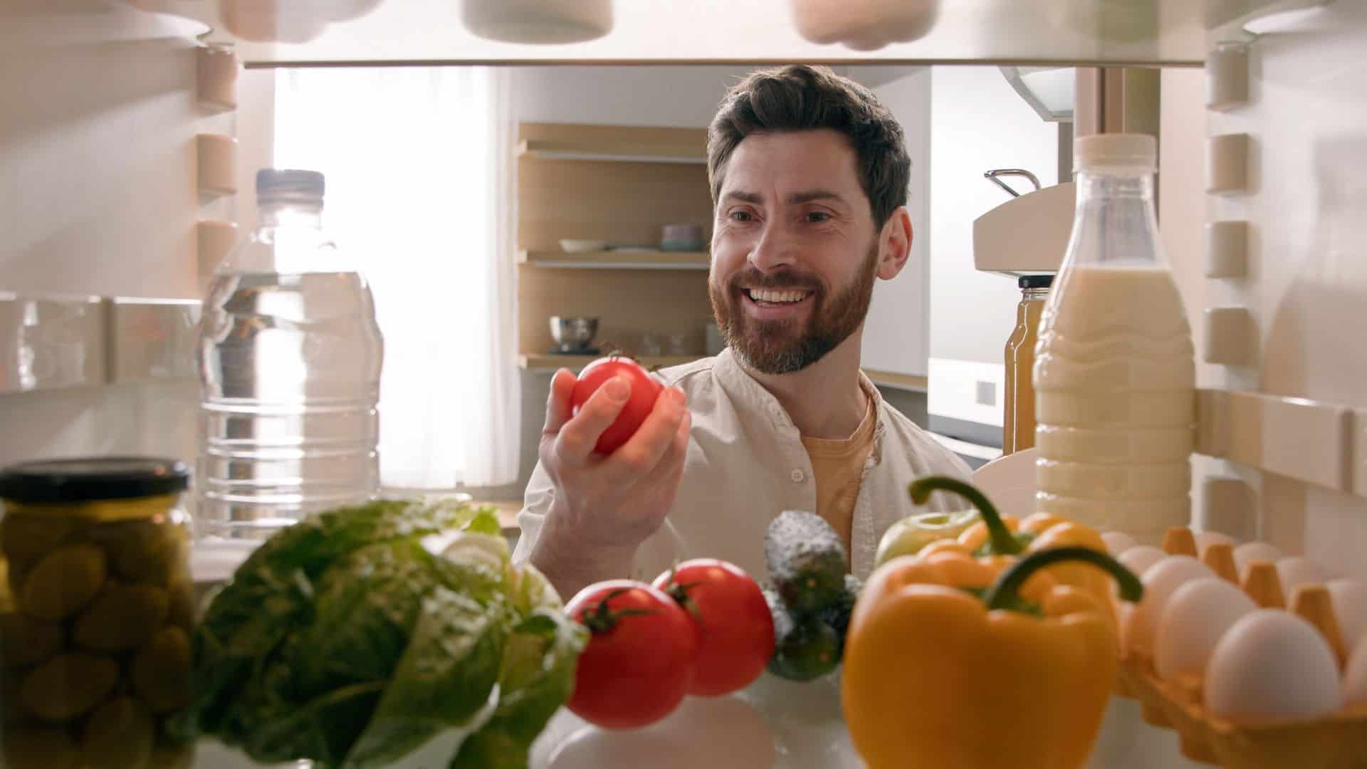 man holding tomato from the fridge