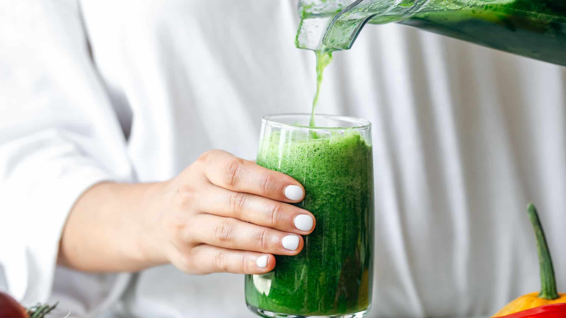 pouring green smoothie into glass