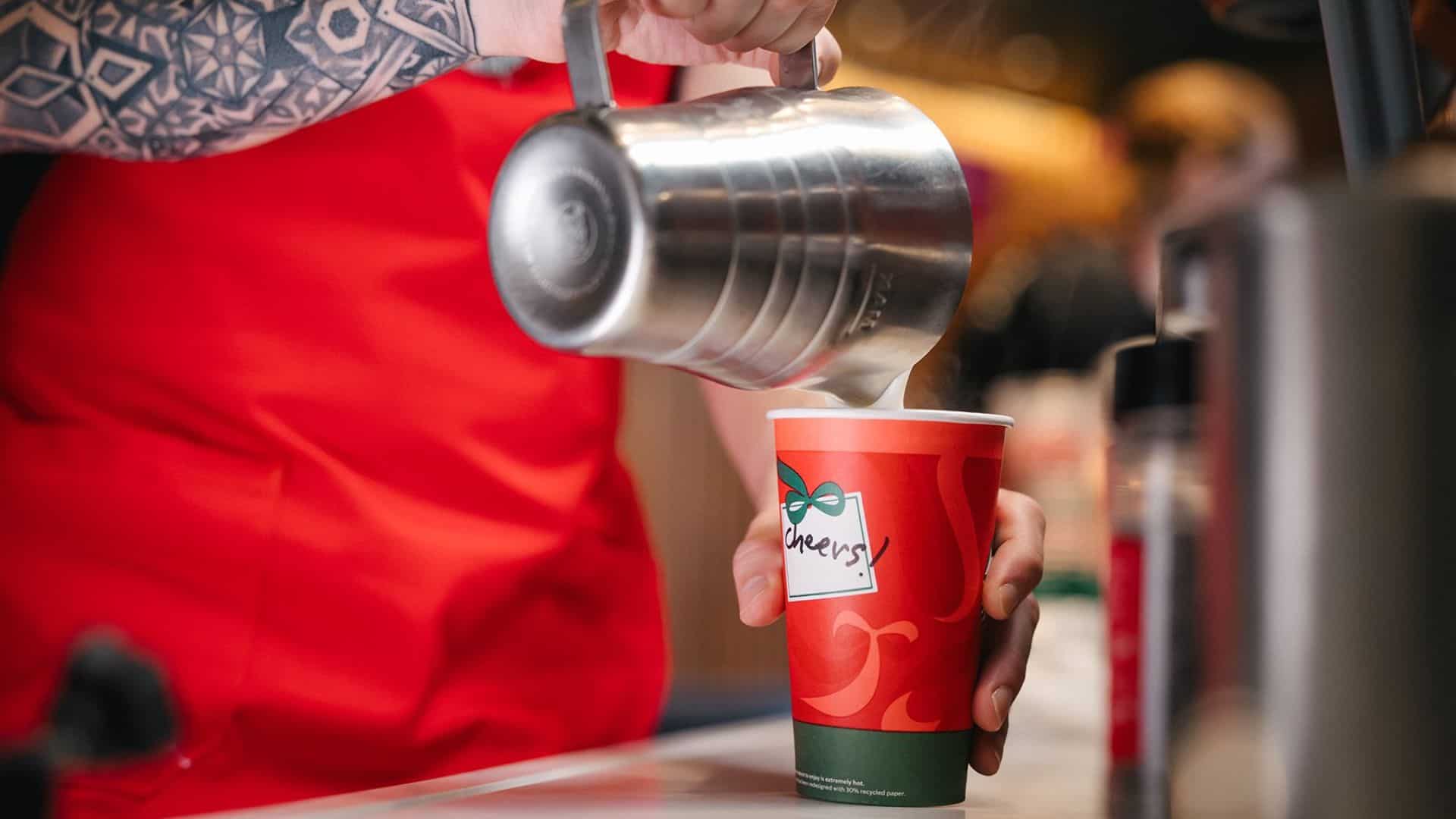 pouring milk into coffee in starbucks holiday cup