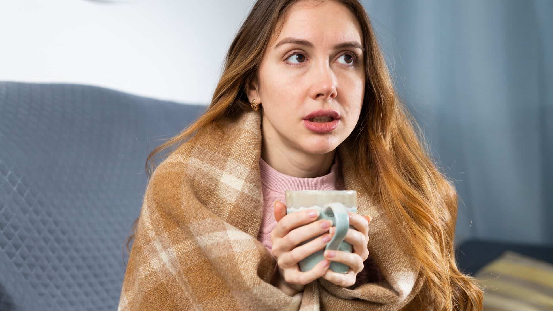 woman holding cup of tea in blanket