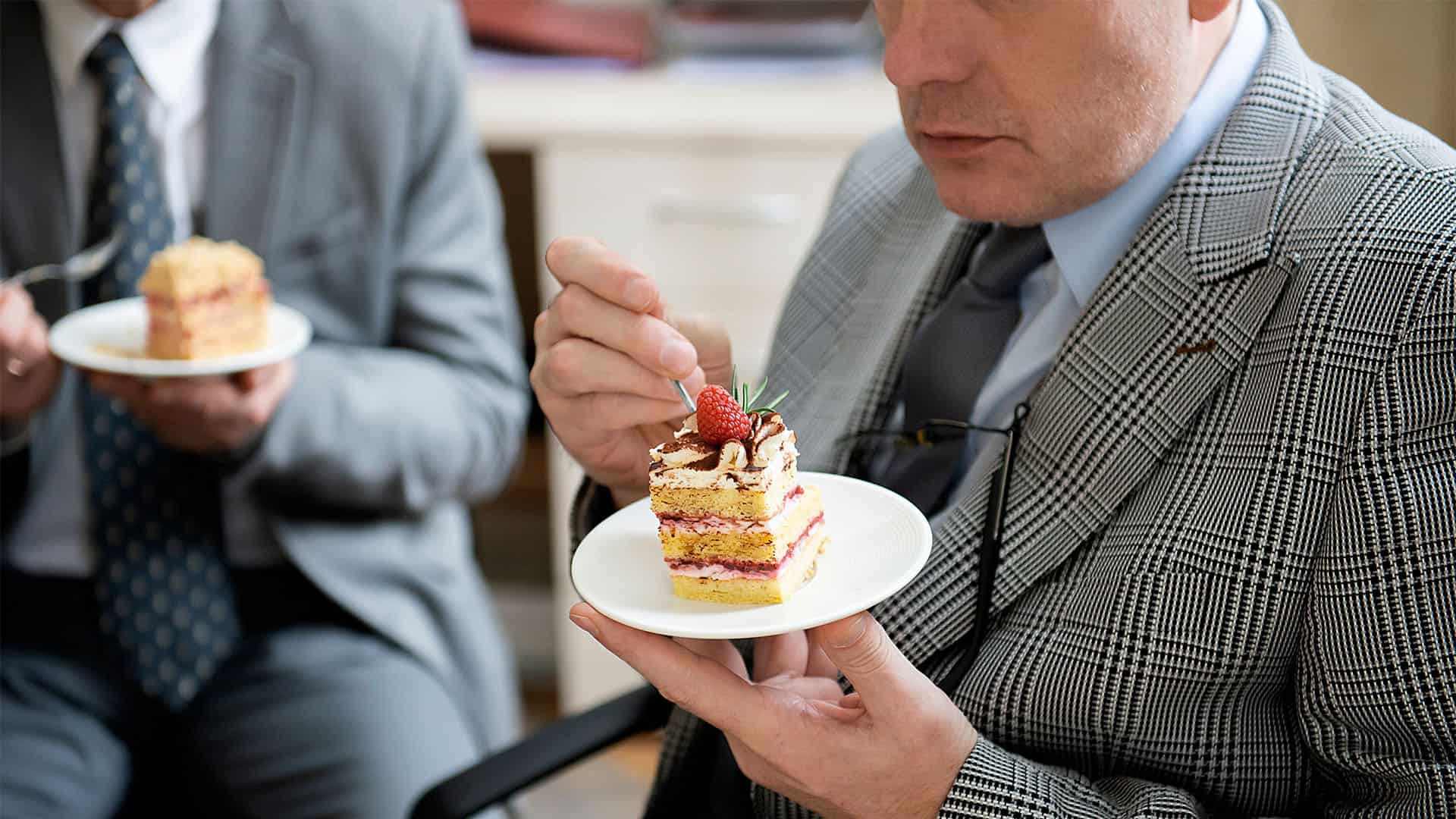 Man eating a cake in office.