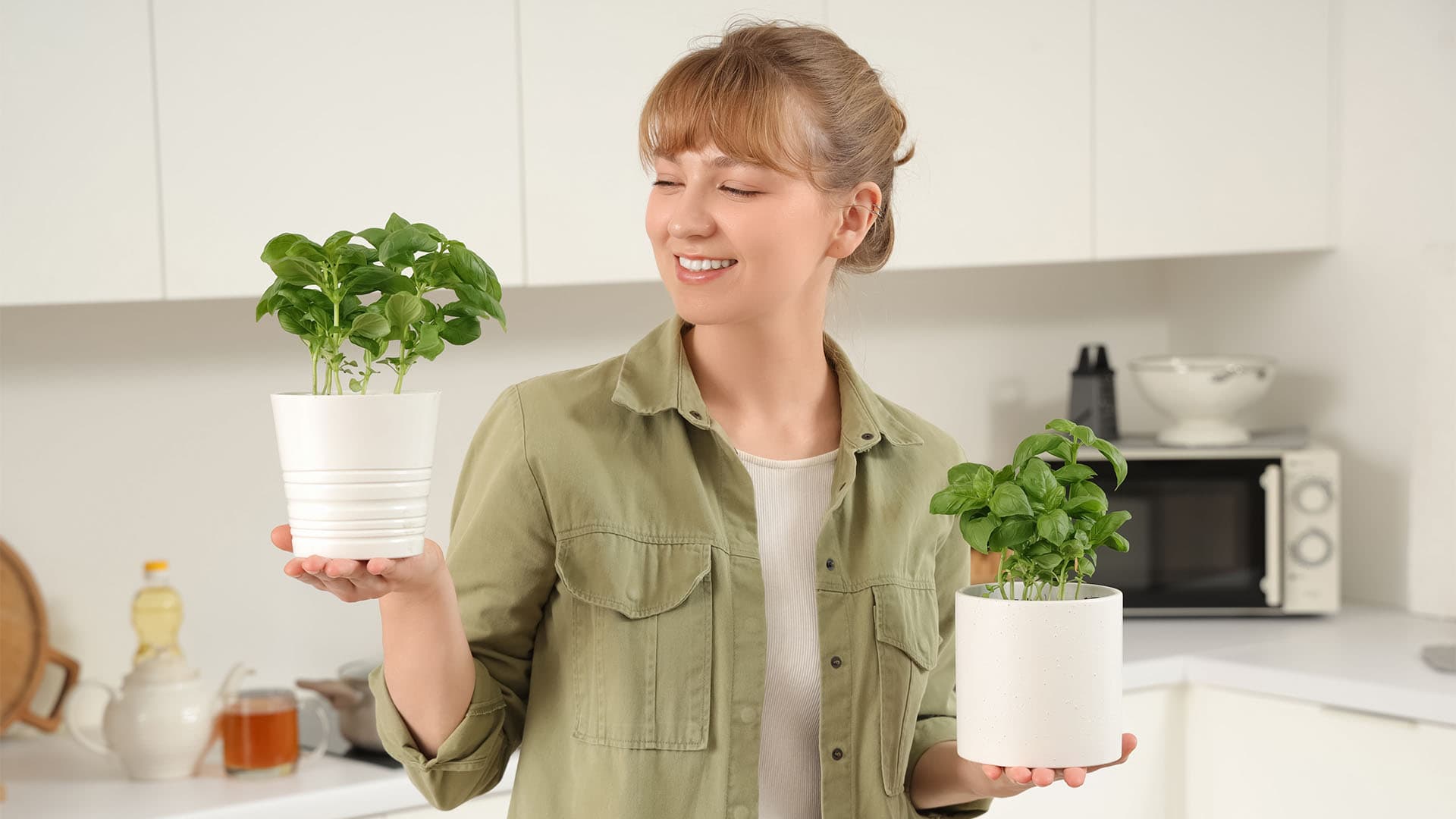 Woman with basil plants in the kitchen.
