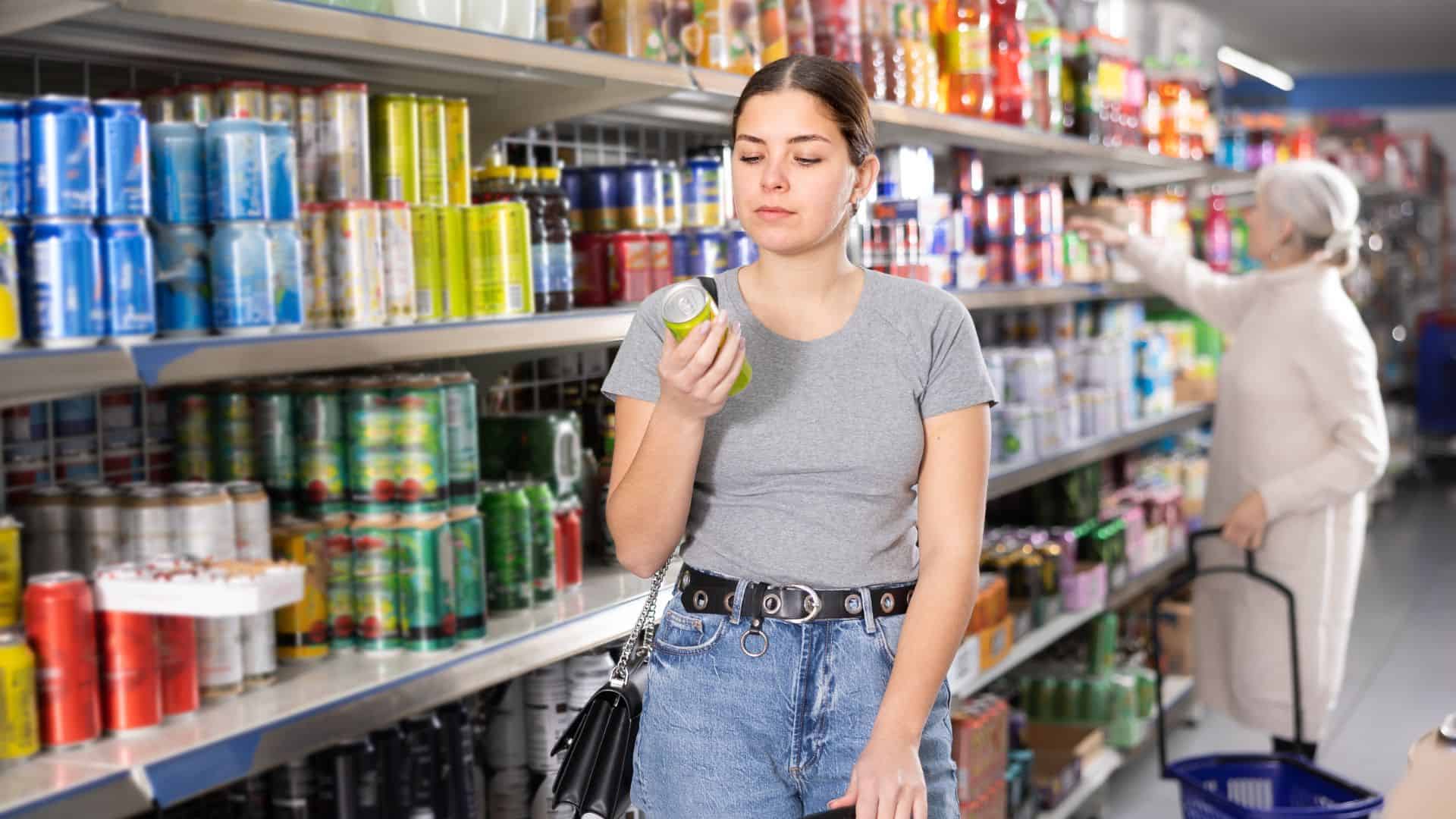 woman reading label on a can in a grocery store
