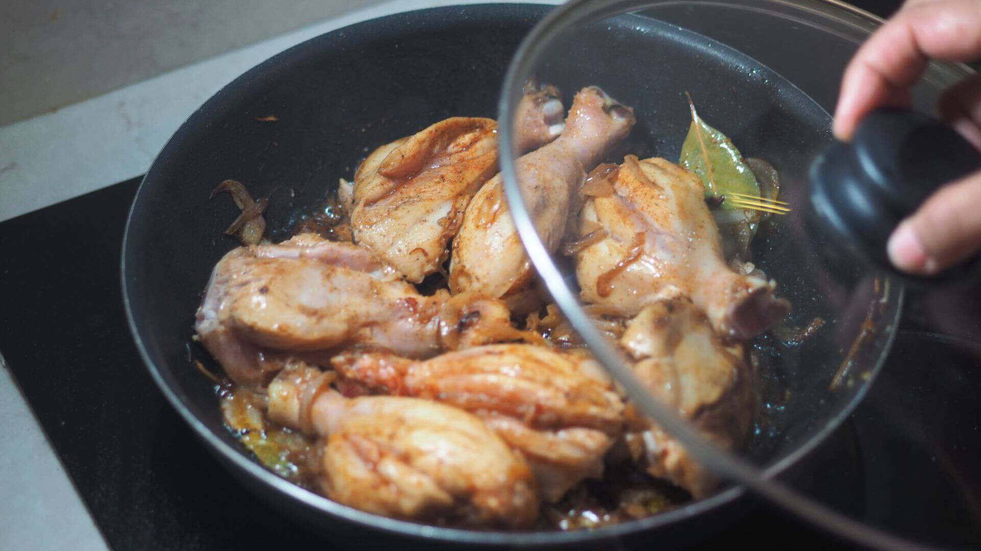 Cooking chicken with herbs in a frying pan on the stove
