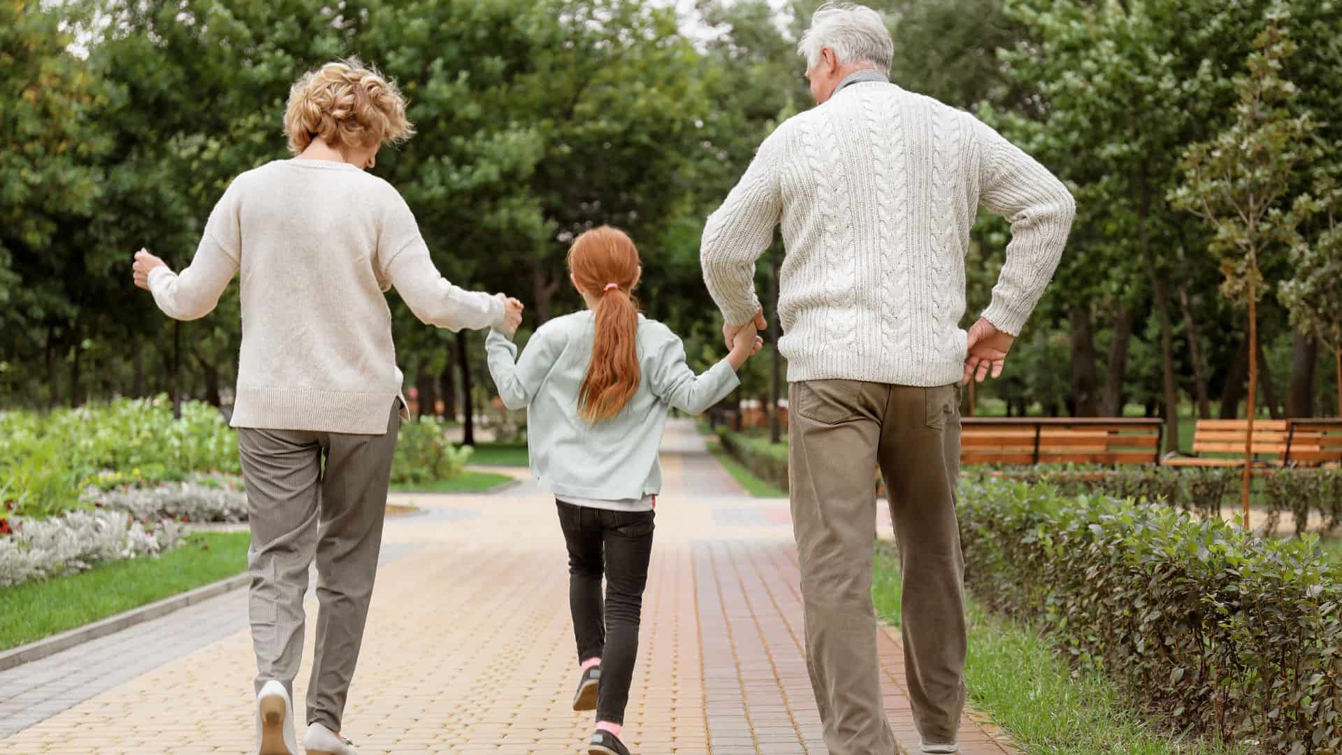 Little Girl with Grandparents Walking in Park