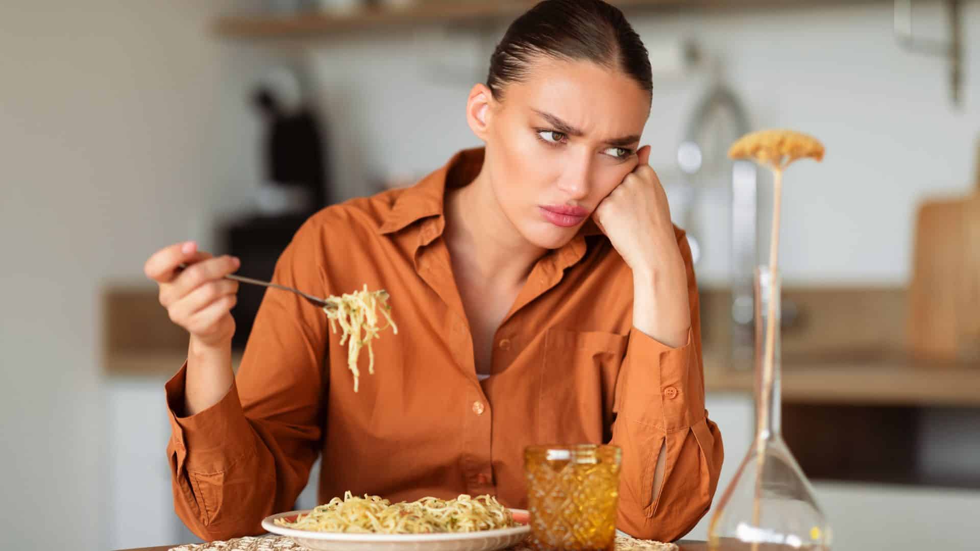 Upset woman eating tasteless pasta